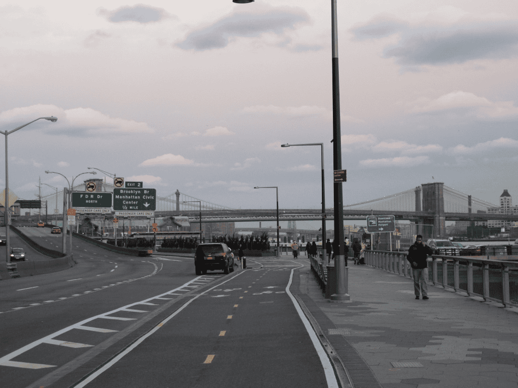 브루클린 다리(Brooklyn Br) 방향을 가리키는 초록색 이정표와 멀리 보이는 브루클린 대교의 실루엣